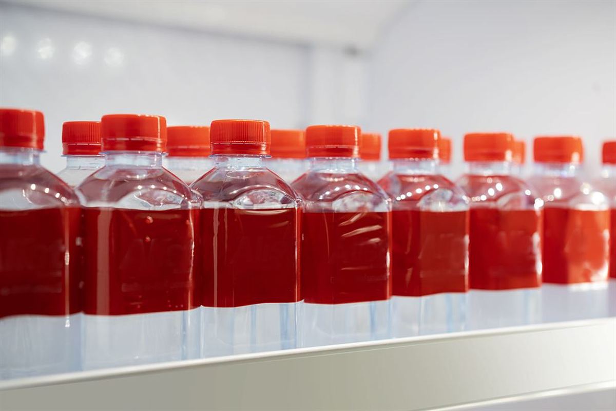 Row of bottles filled with red fruit beverage on a production line shelf