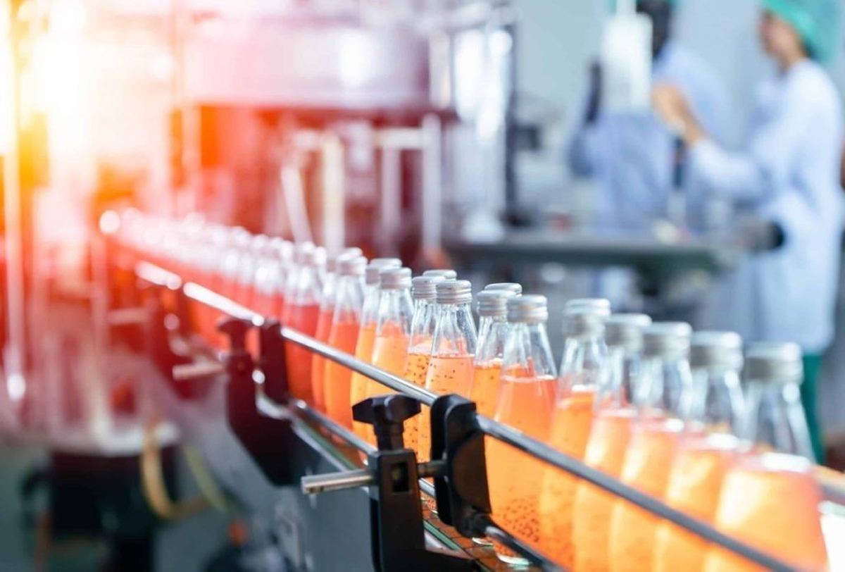 Bottles of orange beverage being filled on a food and beverage production line