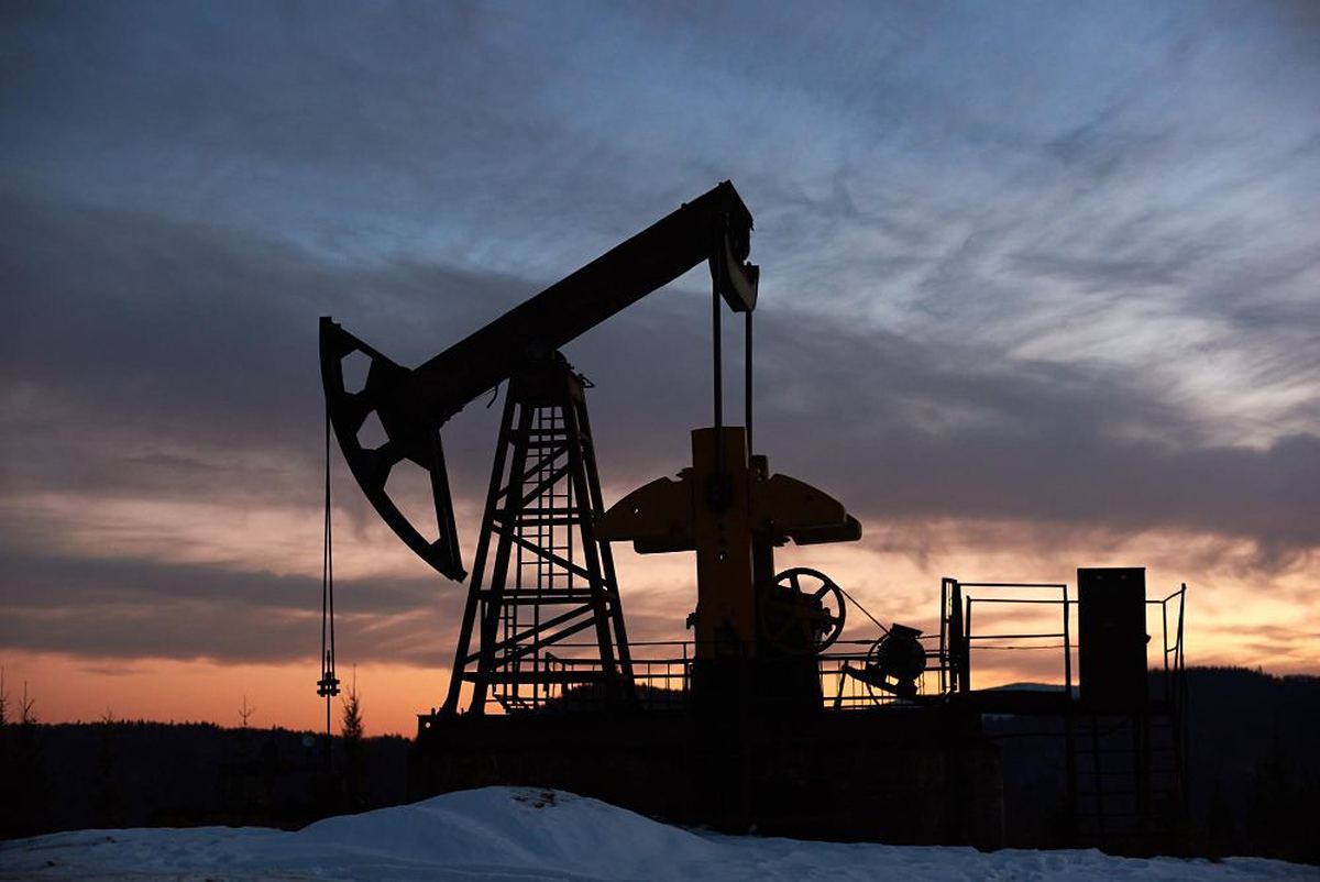 Oil pump jack silhouetted against a sunset at an extraction site