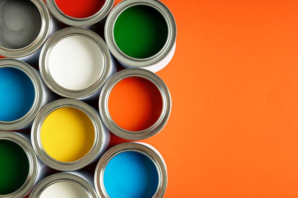 Open paint cans in assorted colours viewed from above on an orange background