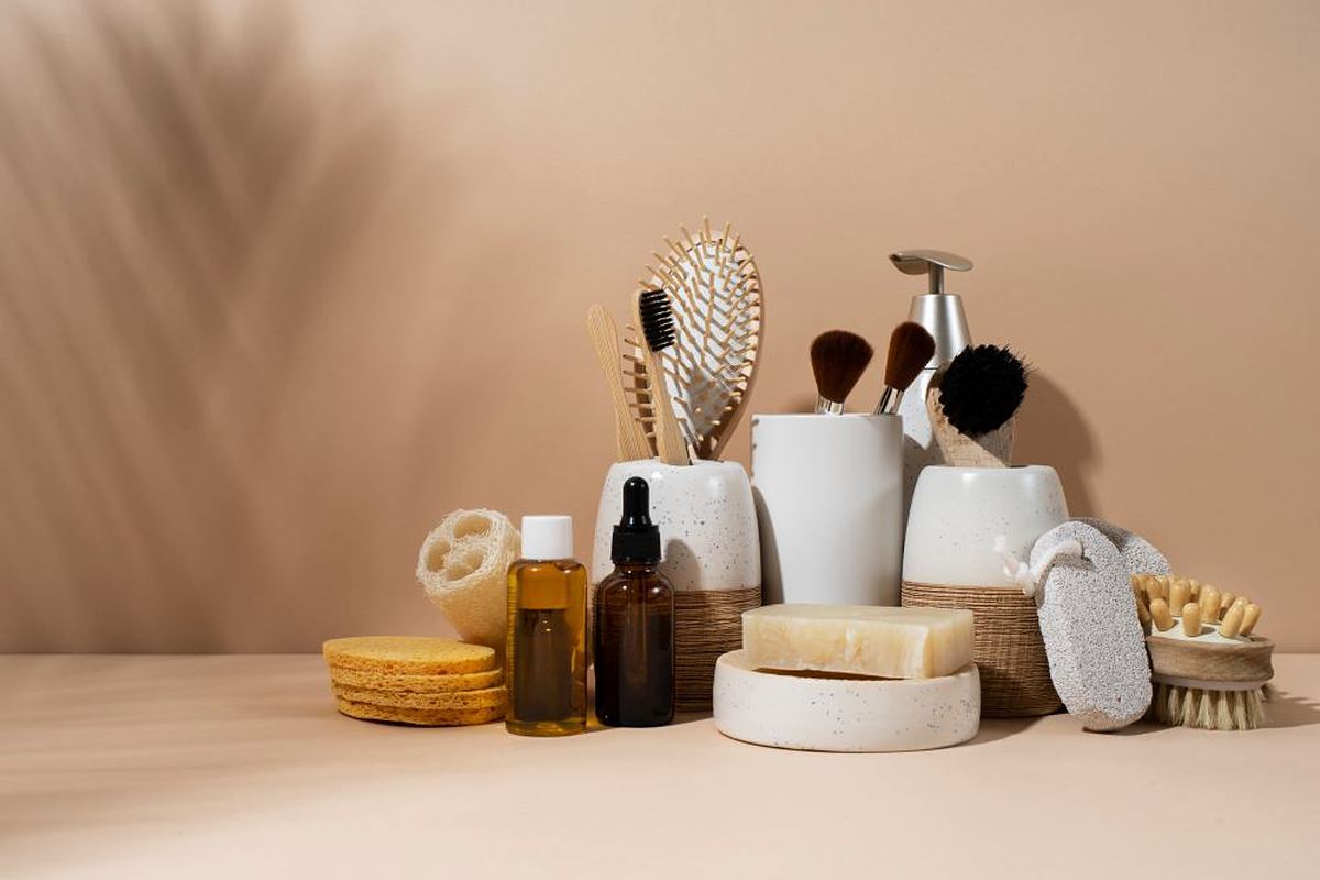 Set of personal grooming items including brushes, soap, oils and sponges on a beige background